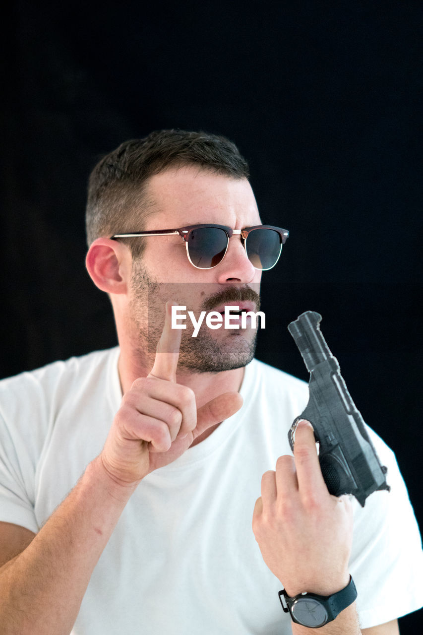 Man touching gun against black background