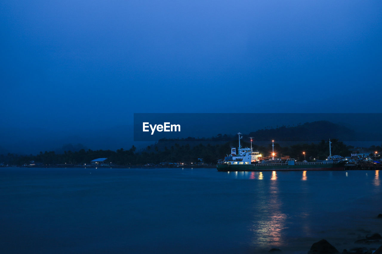 Scenic view of river against blue sky at night