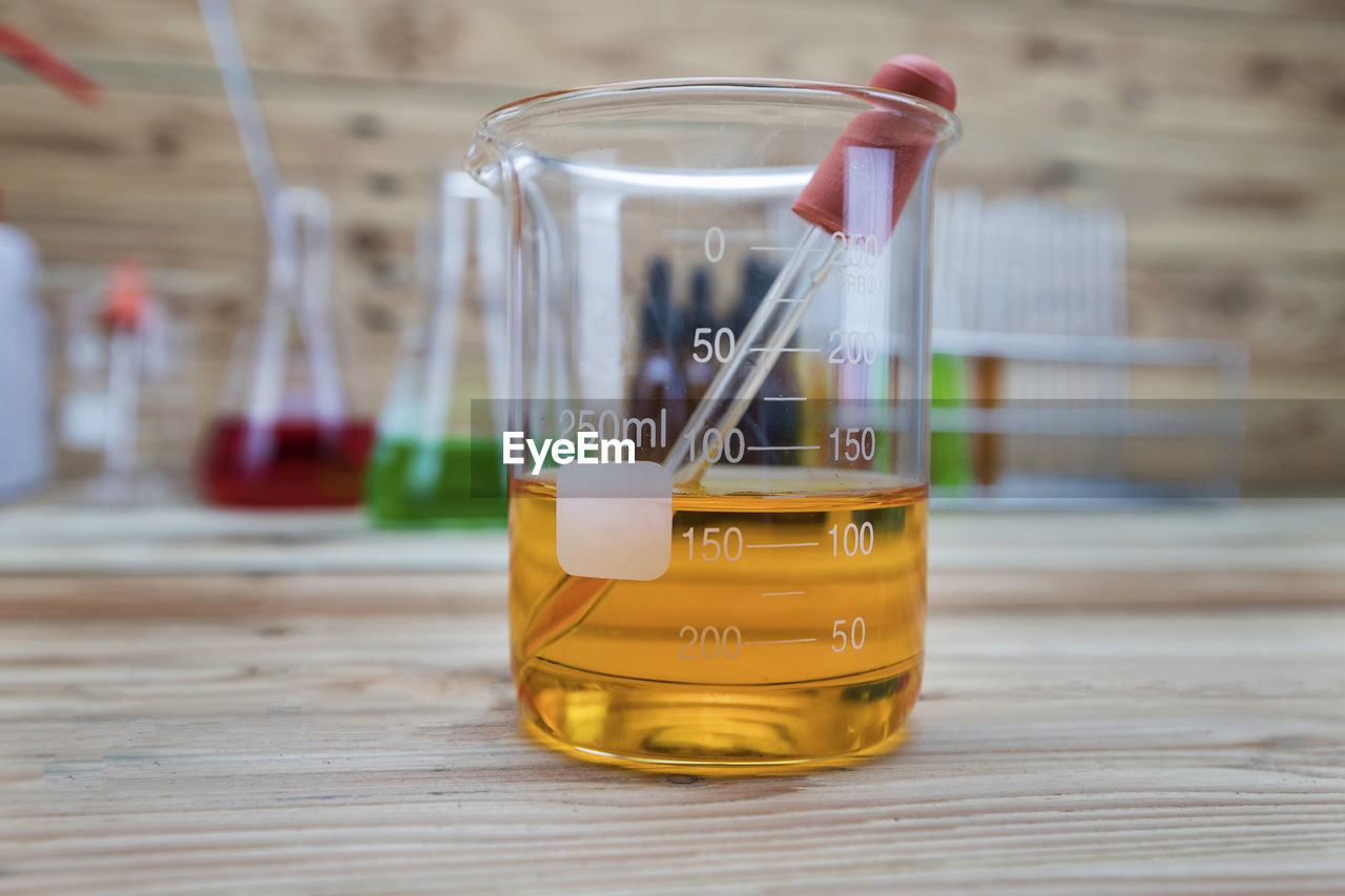 research, scientific experiment, science, laboratory, healthcare and medicine, indoors, education, laboratory glassware, chemistry, test tube, container, biochemistry, no people, biology, medical research, focus on foreground, close-up, table, glass, wood, yellow, biotechnology, chemical, beaker, drink