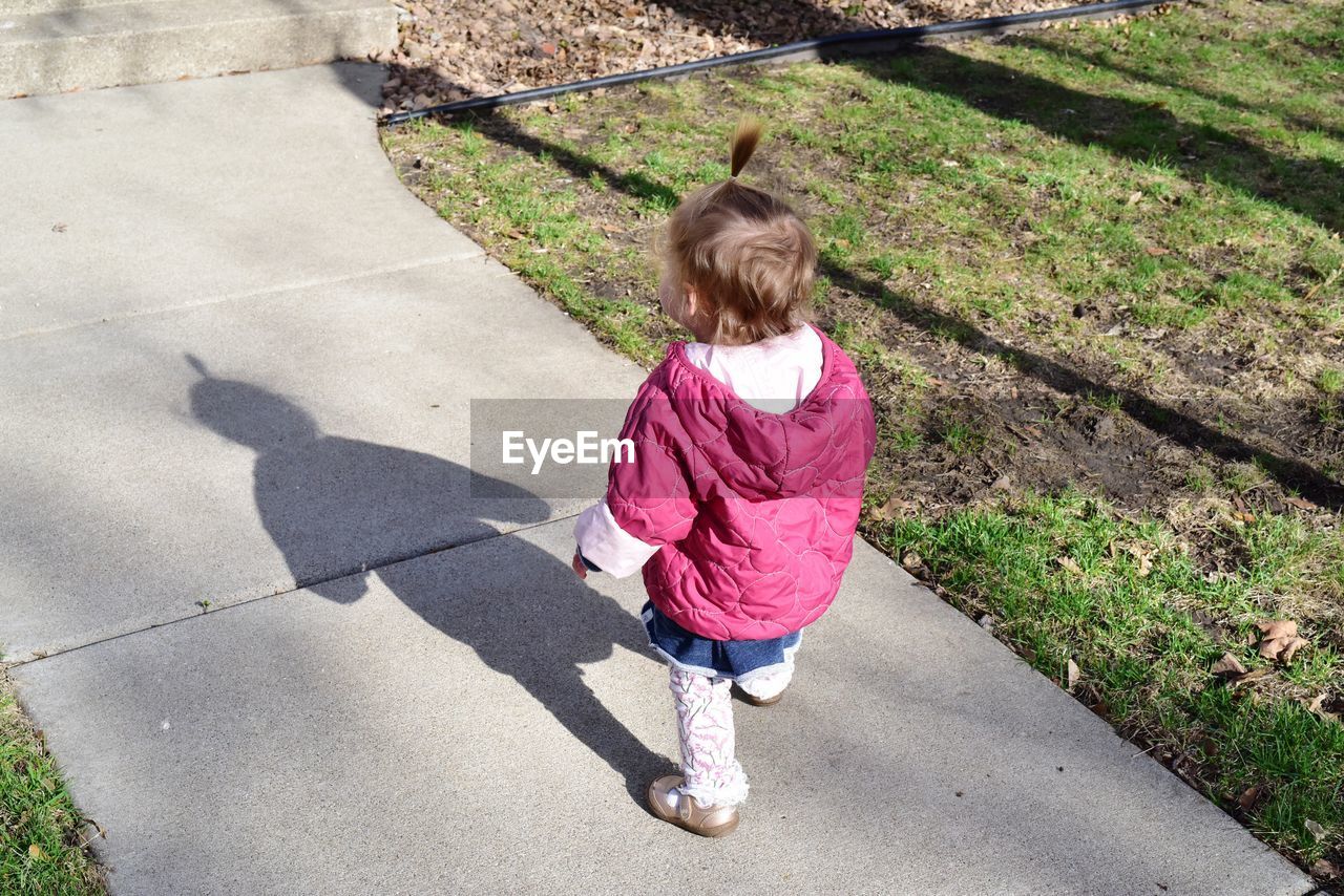 High angle view of baby girl in warm clothing walking on footpath