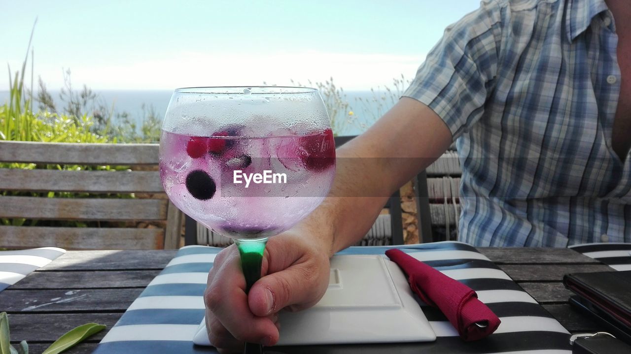 CLOSE-UP OF HAND HOLDING DRINK