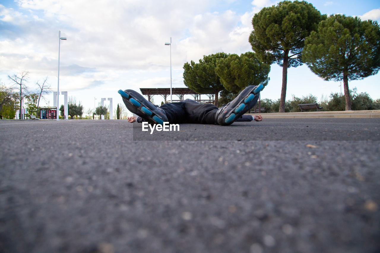 Low section of man with roller skates lying on road