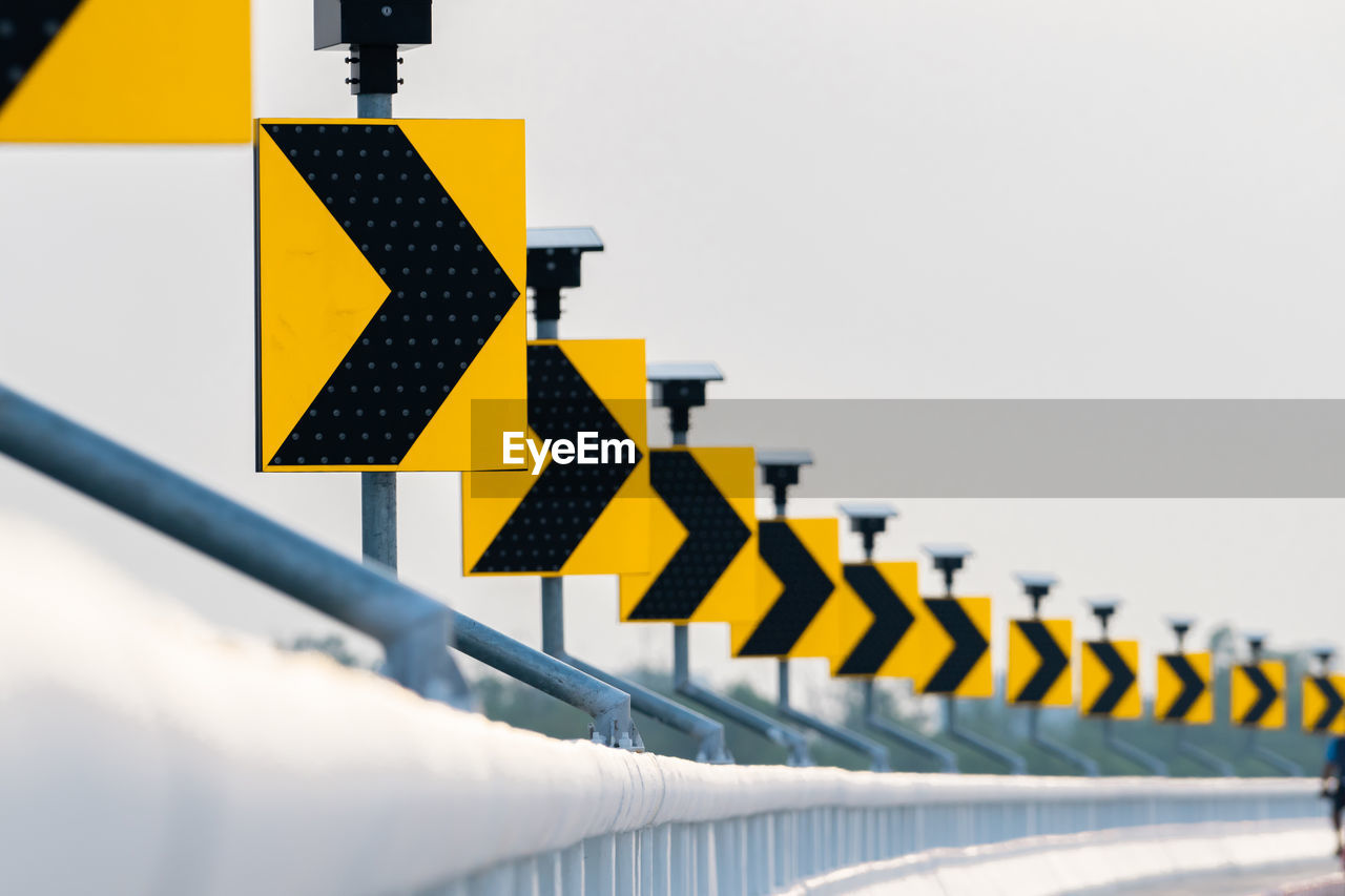 Row of yellow directional signs on railing