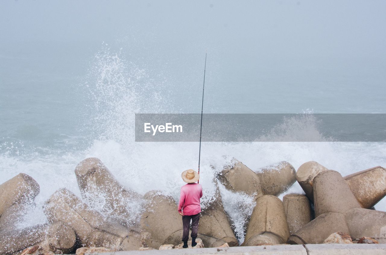 Full length of man fishing on rock in sea