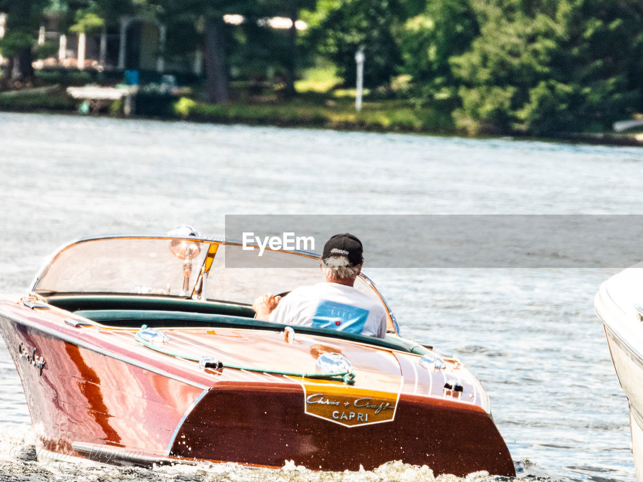 PORTRAIT OF MAN SITTING IN BOAT AGAINST WATER