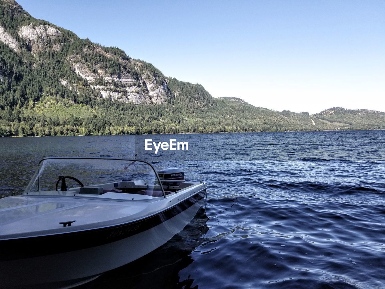 Scenic view of boat on beach with lake against clear blue sky