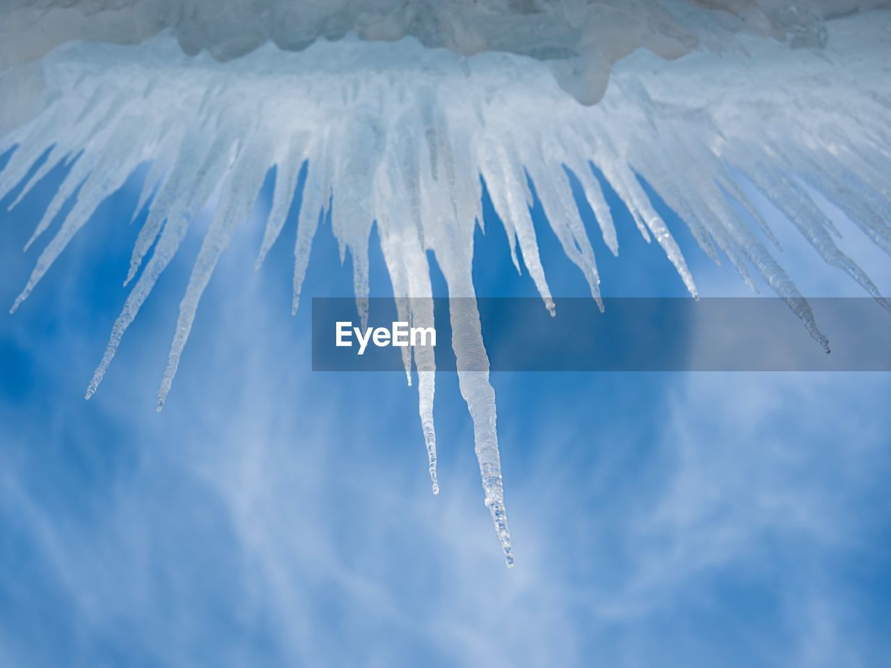 Low angle view of icicles against cloudy sky