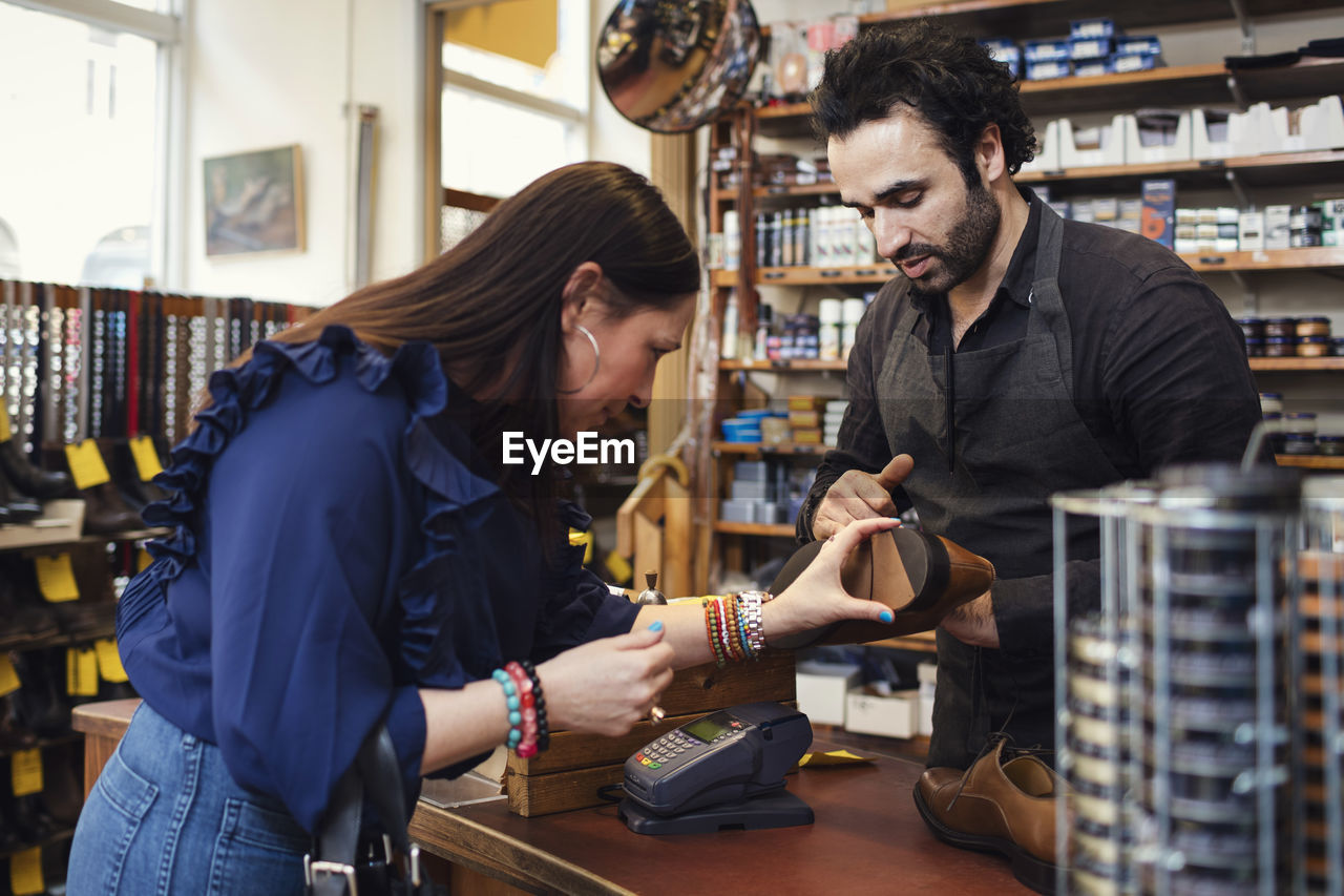 Shoemaker showing shoe to female customer in store