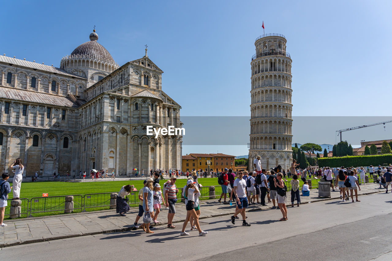 Crowd of tourists visit leaning tower of pisa in summer time