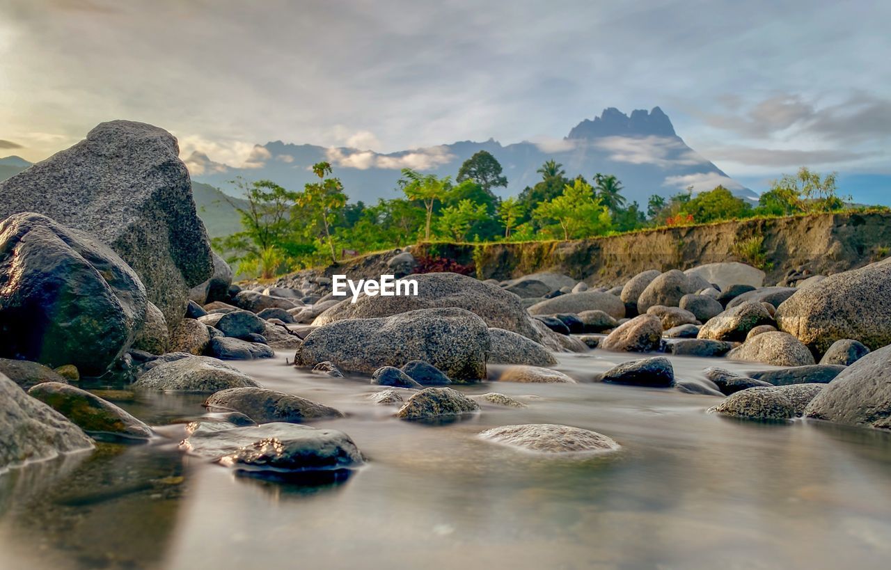 Rocks by lake against sky