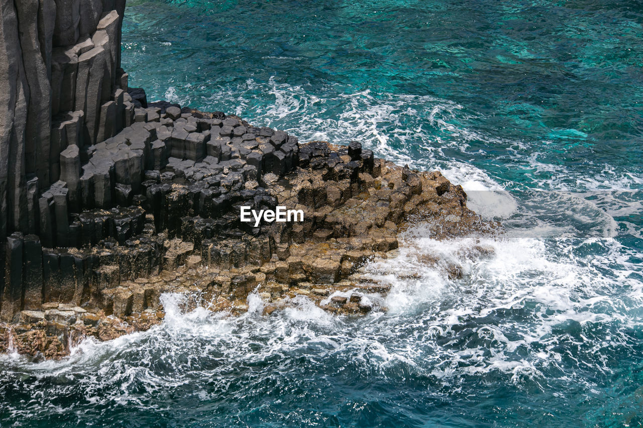 High angle view of waves splashing on rocks