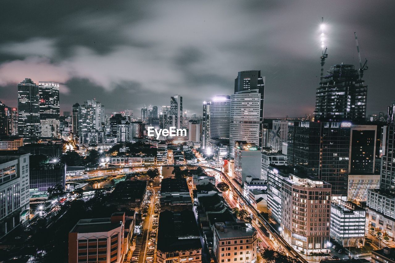 High angle view of cityscape against cloudy sky at night