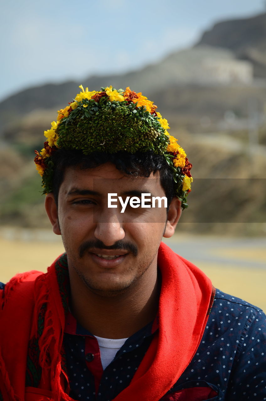 Portrait of young man wearing flowers outdoors