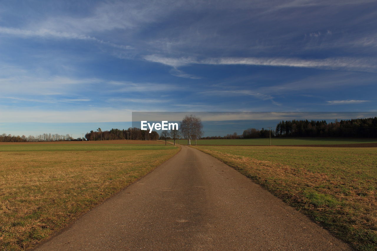 Road amidst field against sky