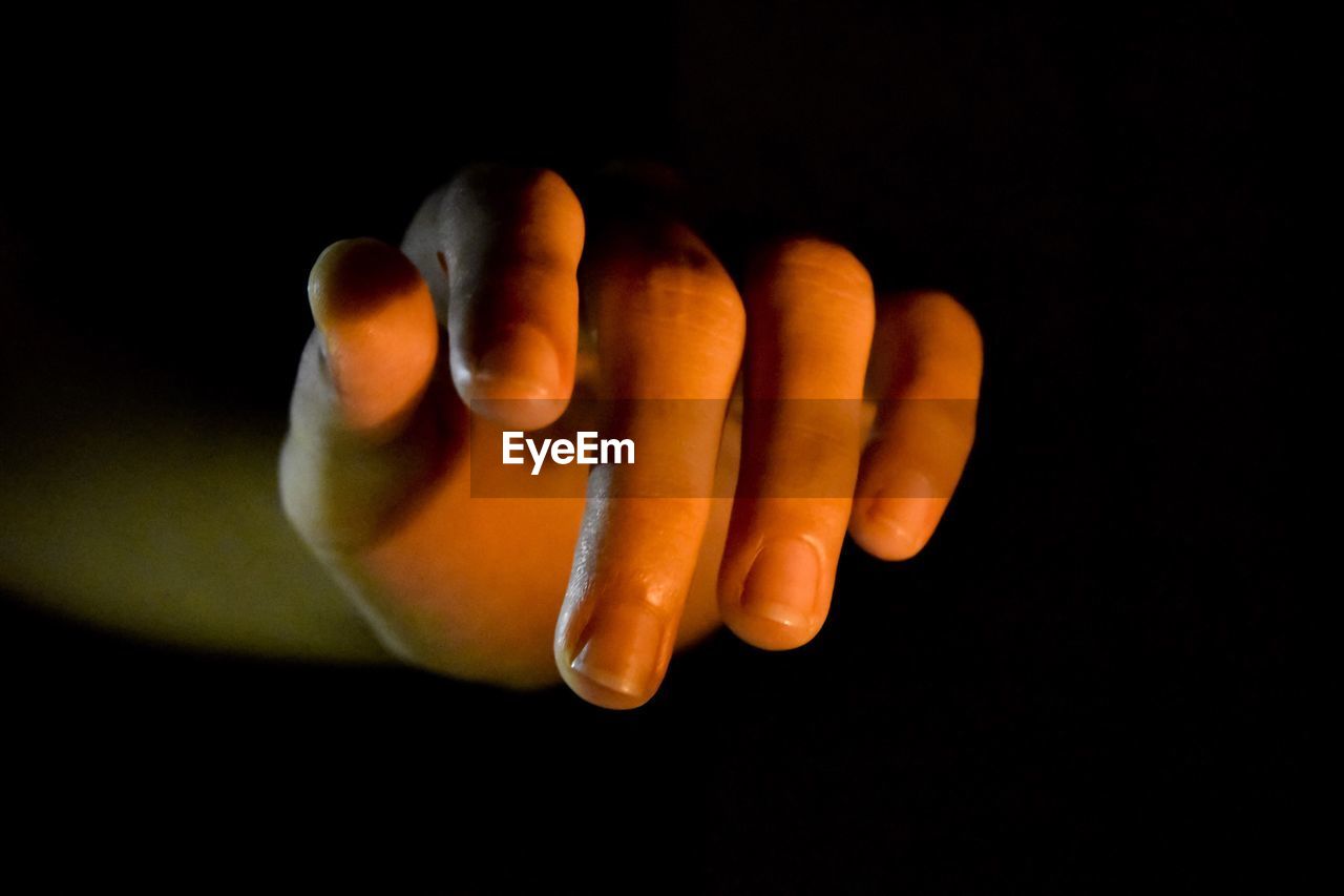 Close-up of human hand against black background