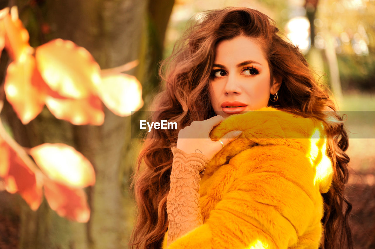 Beautiful young woman wearing jacket standing at park