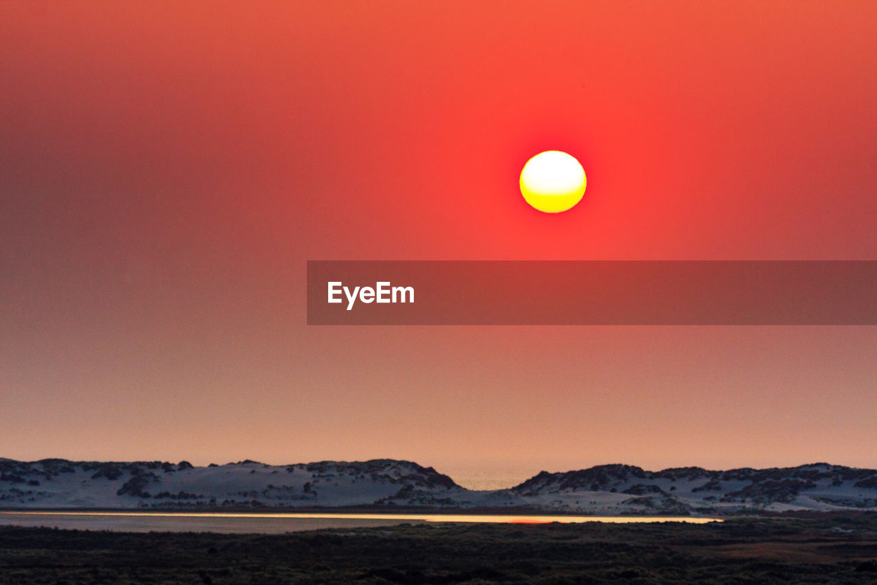 Scenic view of sea against orange sky