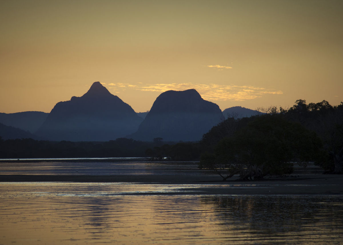 Scenic view of lake by silhouette mountains against sky during sunset