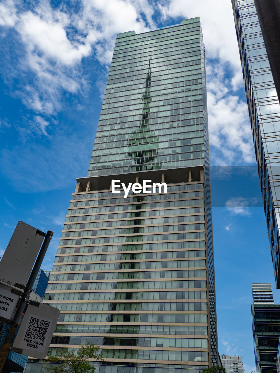 LOW ANGLE VIEW OF MODERN GLASS BUILDING AGAINST SKY