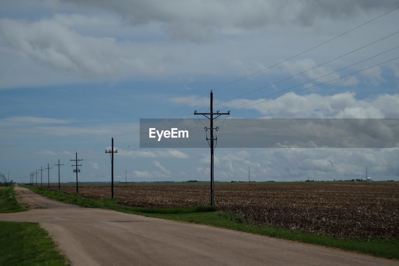 ELECTRICITY PYLON BY ROAD AGAINST SKY