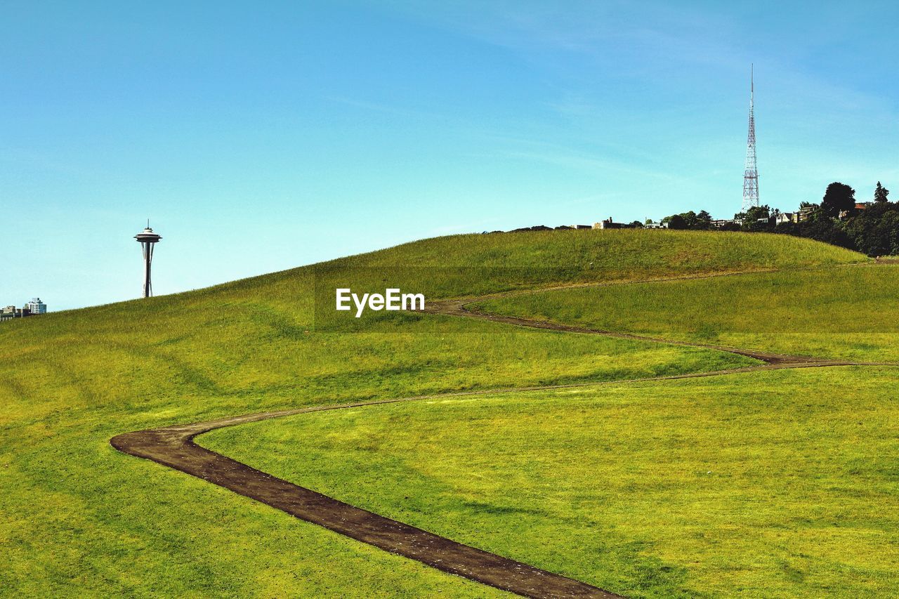 Distant view of space needle in front of green landscape against blue sky