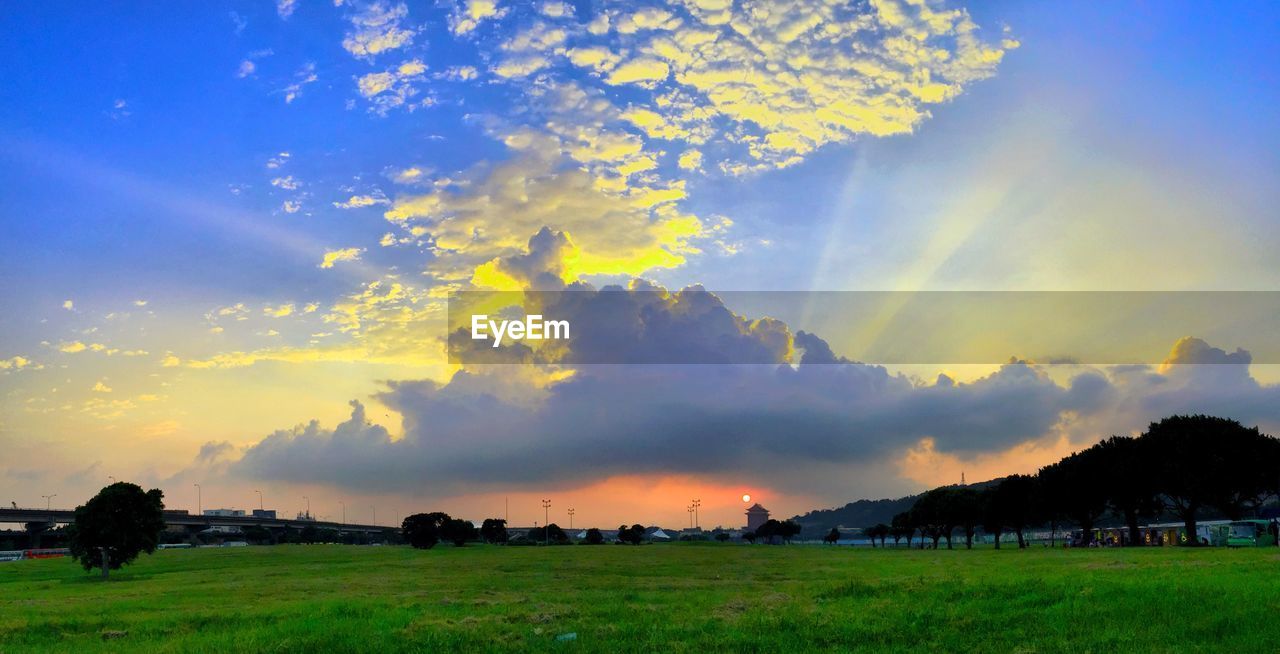 SCENIC VIEW OF GRASSY FIELD AGAINST DRAMATIC SKY