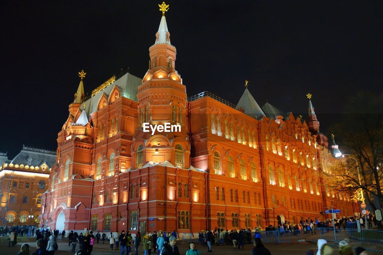 Crowd visiting illuminated historic building against clear sky at night