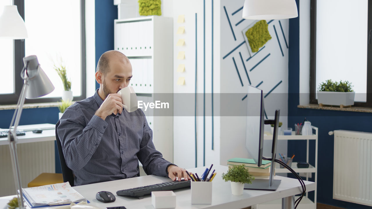 Businessman drinking coffee sitting at desk at office