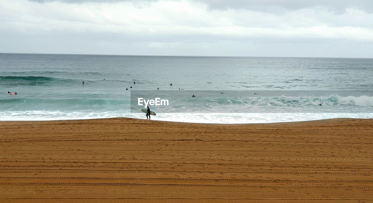 High angle view of man holding surfboard at beach