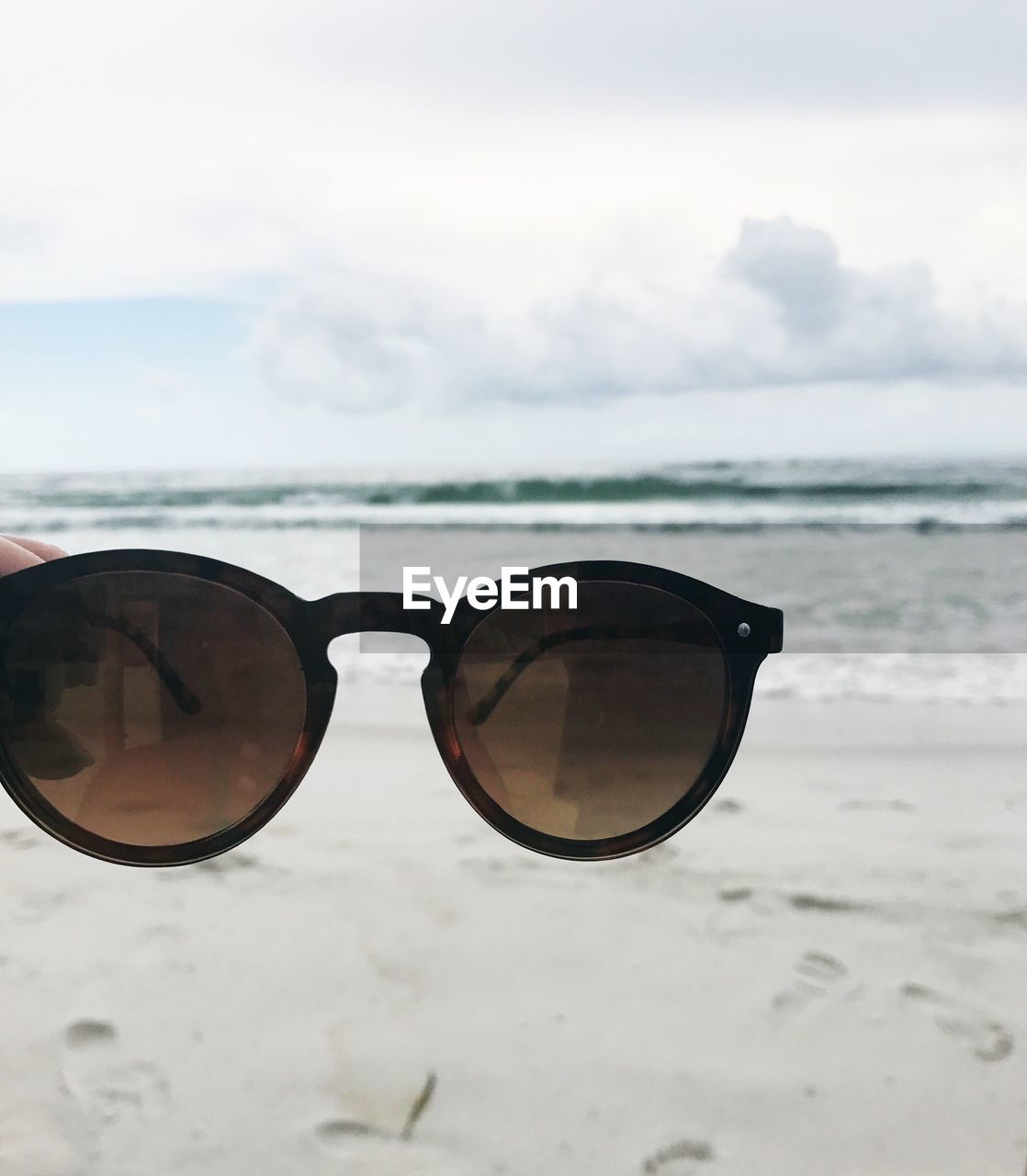 Close-up of sunglasses on beach against sky