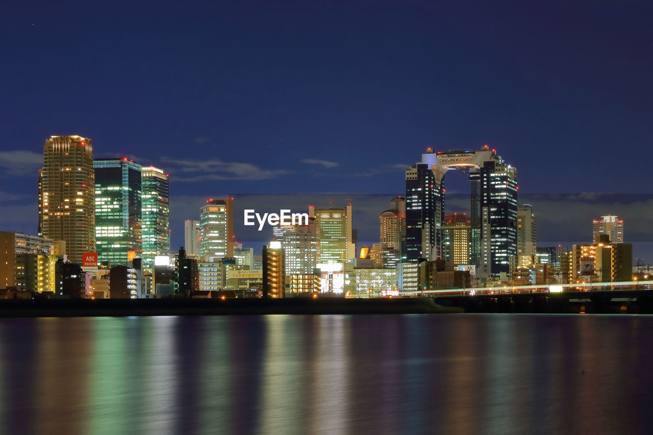 Illuminated cityscape by yodo river against sky at night