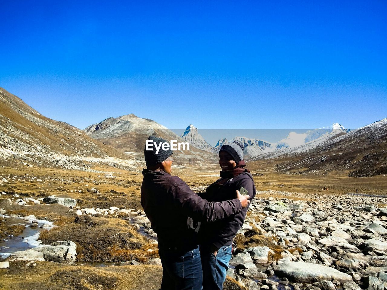 WOMAN STANDING ON MOUNTAIN AGAINST CLEAR SKY