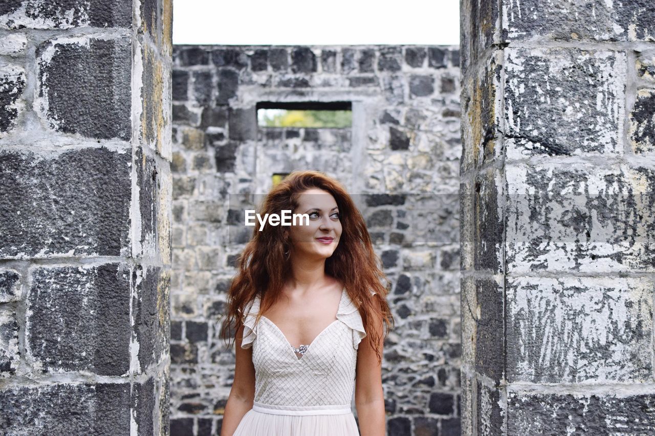 Smiling woman standing at abandoned house