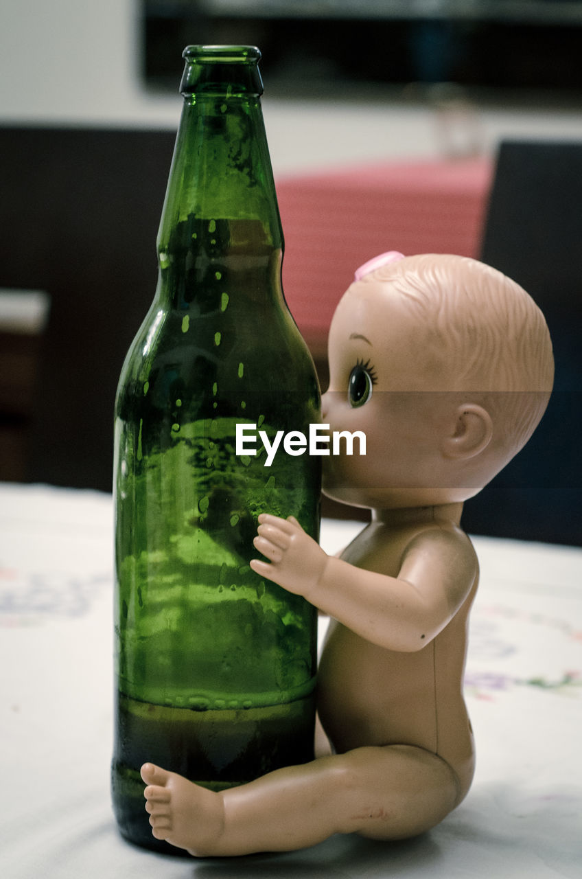 Close-up of alcoholic drink in bottle by doll on table