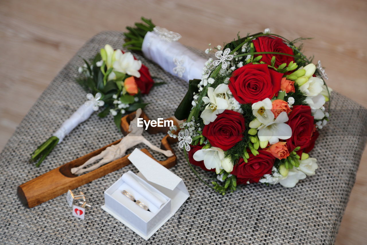 High angle view of bouquet and wedding rings on chair