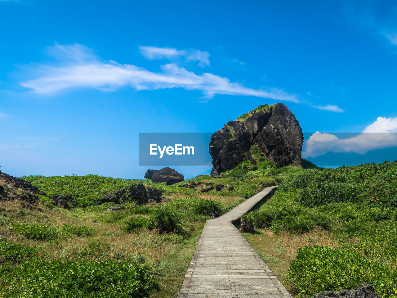 FOOTPATH LEADING TOWARDS MOUNTAIN AGAINST BLUE SKY