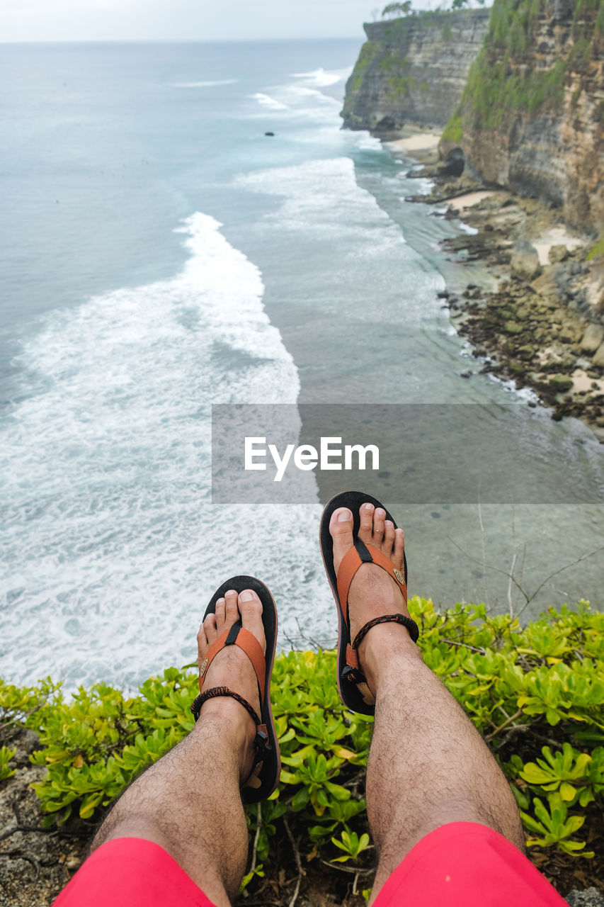 Low section of man relaxing on rock cliff at beach