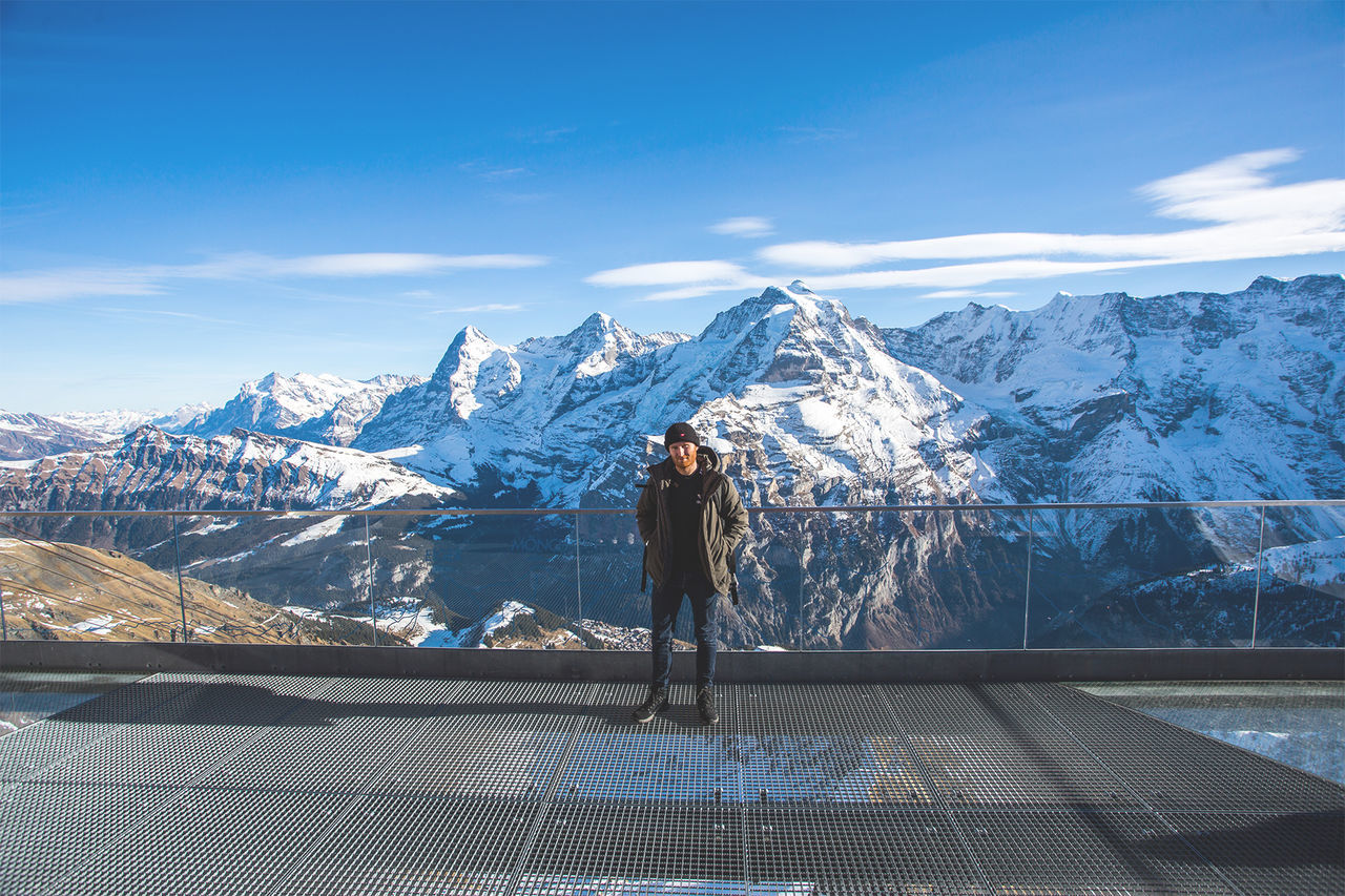 Hiker standing on observation point against snowcapped mountains