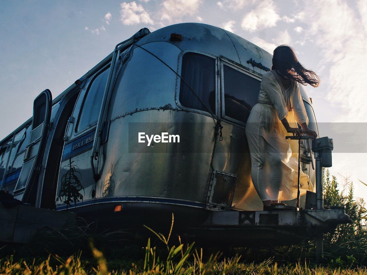 Low angle view of woman standing on travel trailer against sky