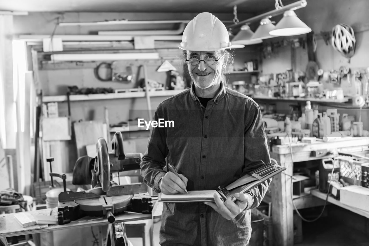 Portrait of carpenter holding checklist in workshop