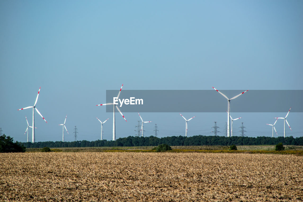 WINDMILLS ON FIELD AGAINST SKY