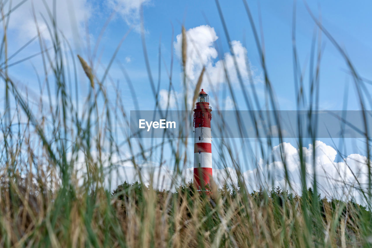 Lighthouse on field against sky