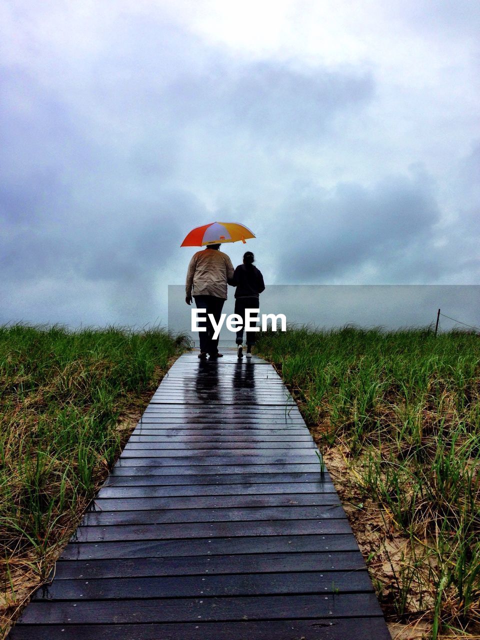 Rear view of couple walking on boardwalk