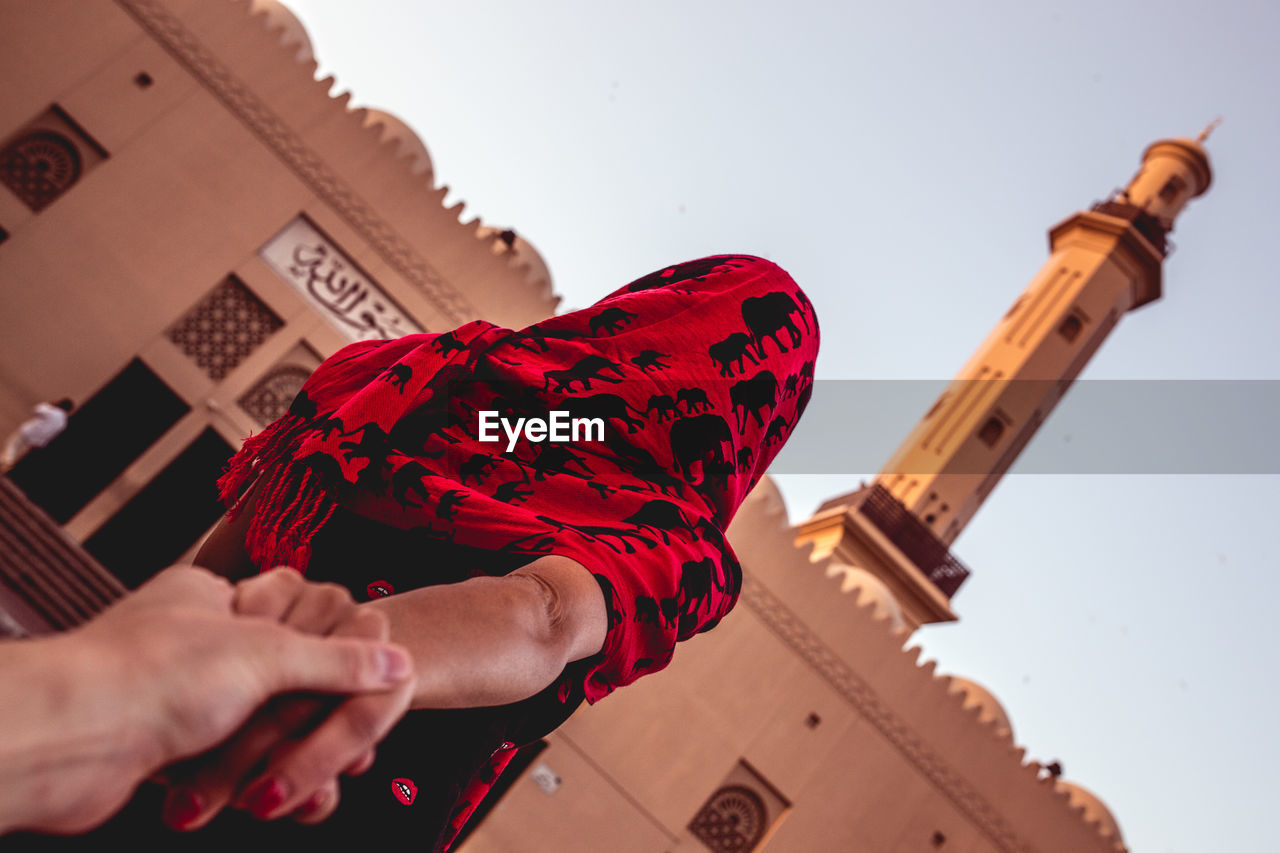 Low angle view of man holding woman hand against building