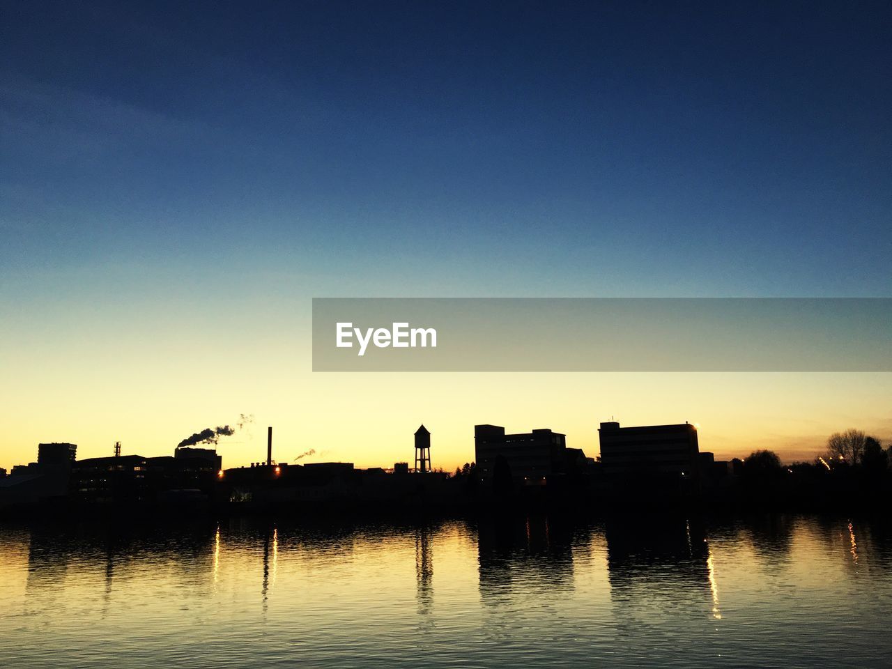 SILHOUETTE BUILT STRUCTURES WITH WATERFRONT AT SUNSET