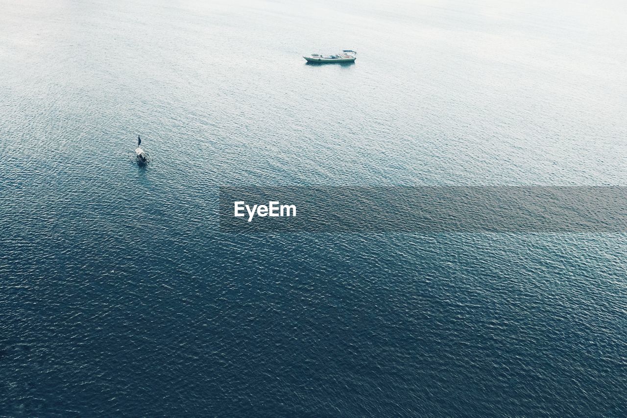 HIGH ANGLE VIEW OF SAILBOATS SAILING ON SEA