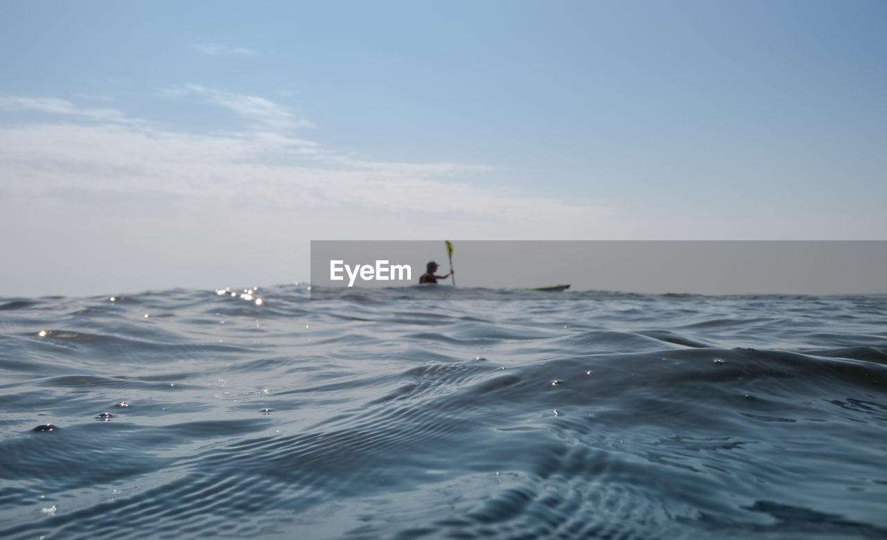 MAN SURFING IN SEA AGAINST SKY