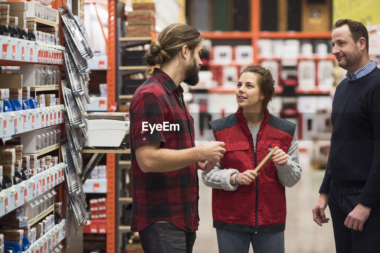 Saleswoman talking to male customers in hardware store