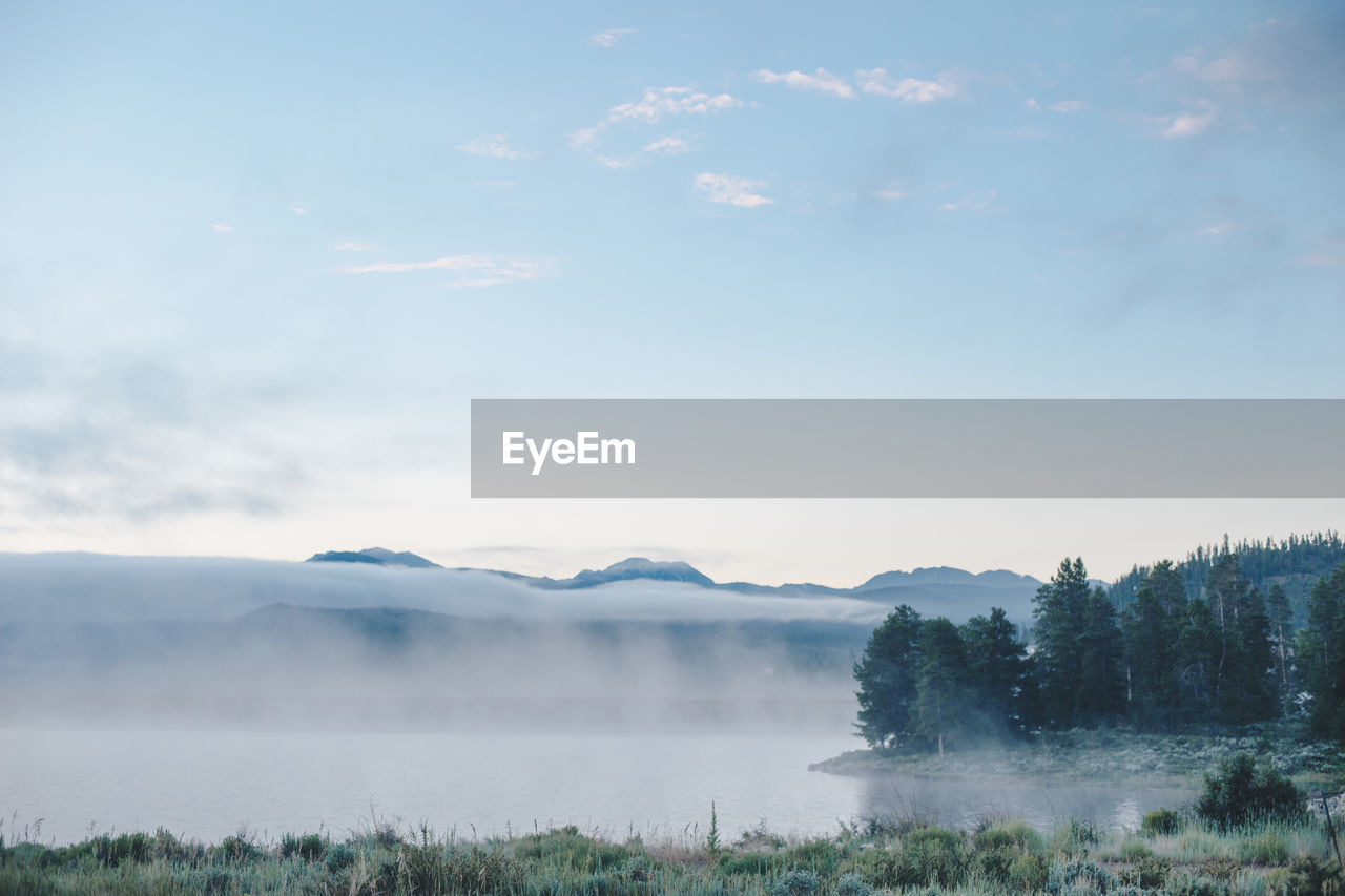 morning, environment, sky, nature, fog, cloud, landscape, mist, scenics - nature, beauty in nature, mountain, plant, tree, tranquility, water, tranquil scene, land, dawn, no people, reflection, lake, forest, blue, winter, non-urban scene, outdoors, day, travel, travel destinations, sunlight, grass, wilderness, sunrise, cold temperature, idyllic, sun, mountain range, rural scene, copy space, horizon