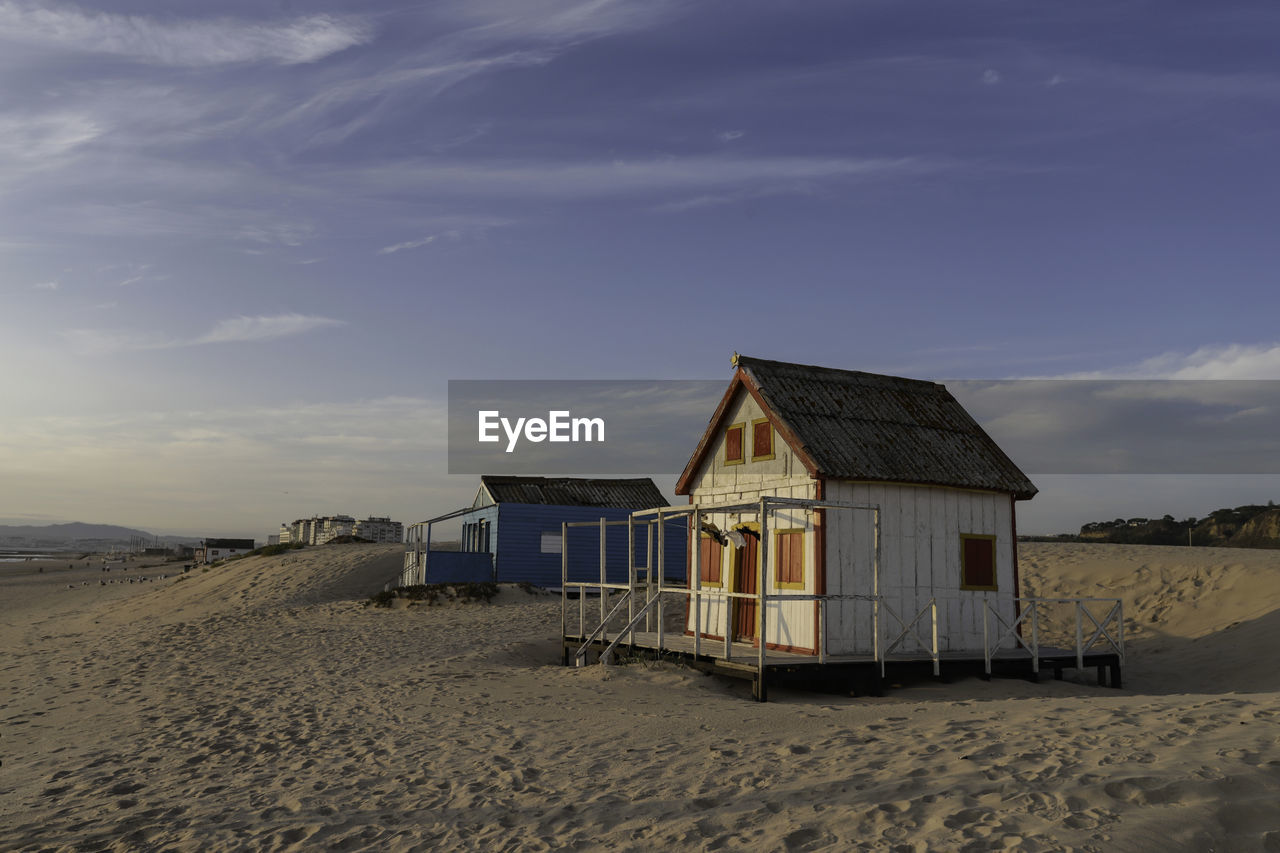 BEACH HUTS BY BUILDINGS AGAINST SKY